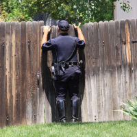 illegal search concept - policeman looking over fence illegal search concept - policeman looking over fence