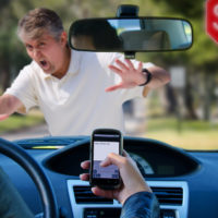 Distracted driver texting with phone is about to hit a pedestrian