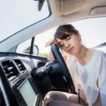 young female driver sleeping behind wheel as part of drowsy driving concept