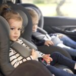 cute small twins in car seats in the car