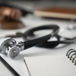 Medical law concept. Gavel, notebook and stethoscope on the white table. Place for text. Medical law concept. Gavel, notebook and stethoscope on the white table. Place for text.