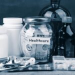 Saving money for health care insurance - money glass, stethoscope, pills and bottles