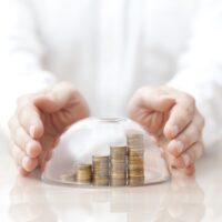 Rising coins protected under a glass dome and hands