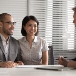 Smiling mixed race family couple meeting real estate agent.