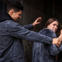 Criminal attacking young woman in alley. Self defense concept